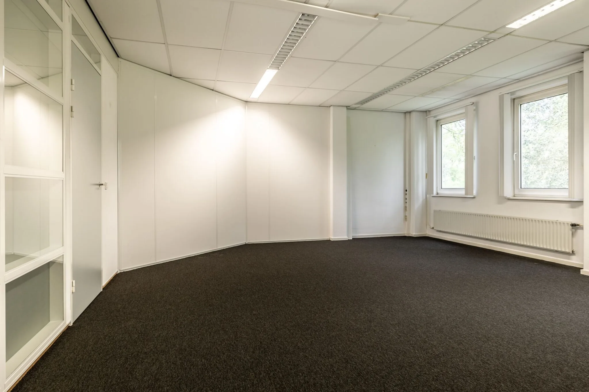 Leeg kantoorruimte met witte wanden, systeemplafond en ramen aan de rechterkant in Paardeweide 2A-4C.