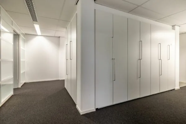 Kantoorruimte met witte inbouwkasten en grijs tapijt in Paardeweide 2A-4C.