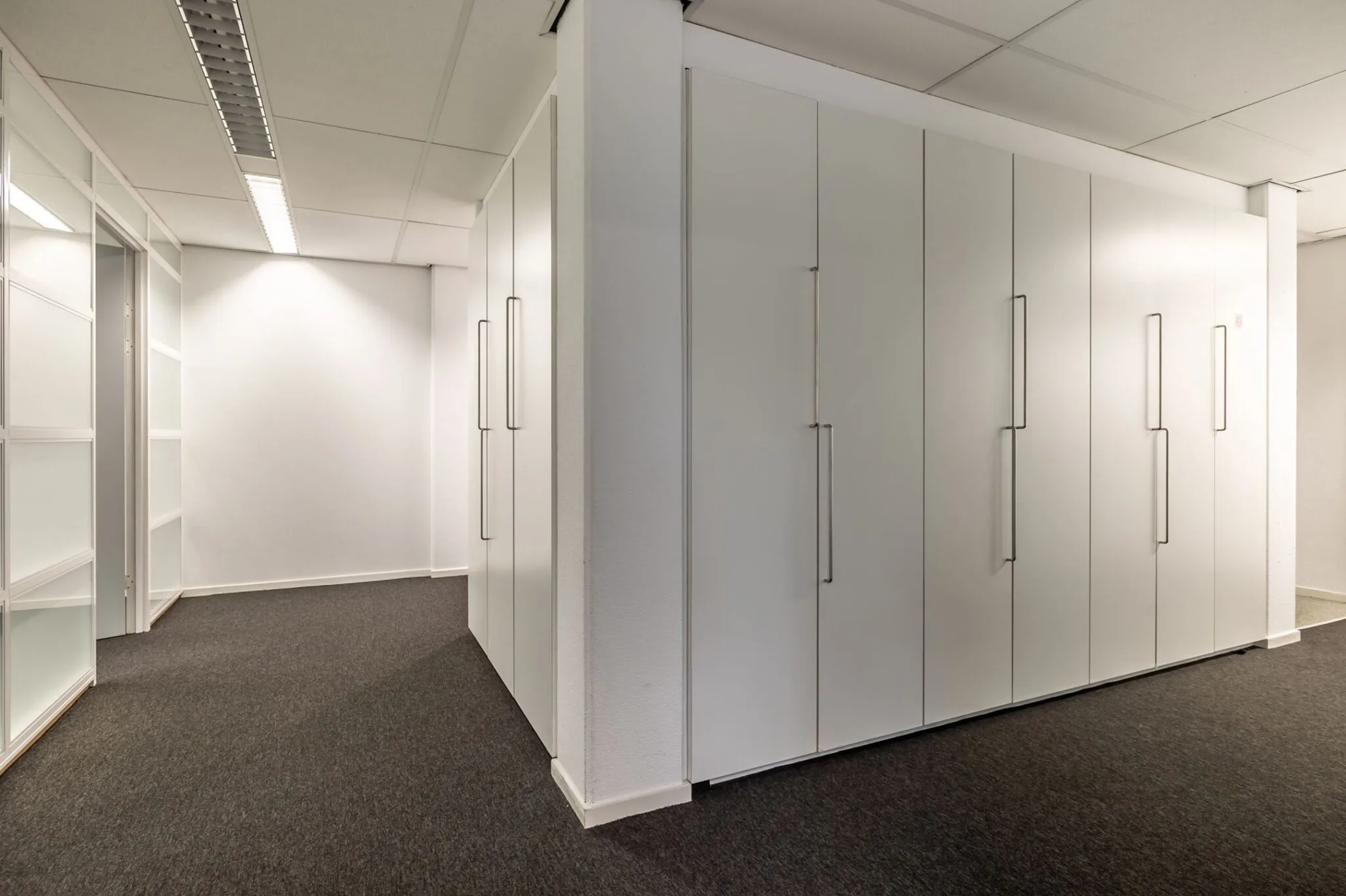 Kantoorruimte met witte inbouwkasten en grijs tapijt in Paardeweide 2A-4C.