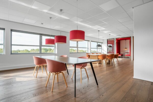 Moderne kantoorruimte aan de Papendorpseweg 75 met grote ramen, houten vloer, kleurrijke stoelen en hanglampen.