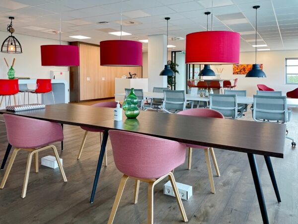 Moderne, kleurrijke kantoorruimte aan de Papendorpseweg 75 met designmeubilair en opvallende rode hanglampen.