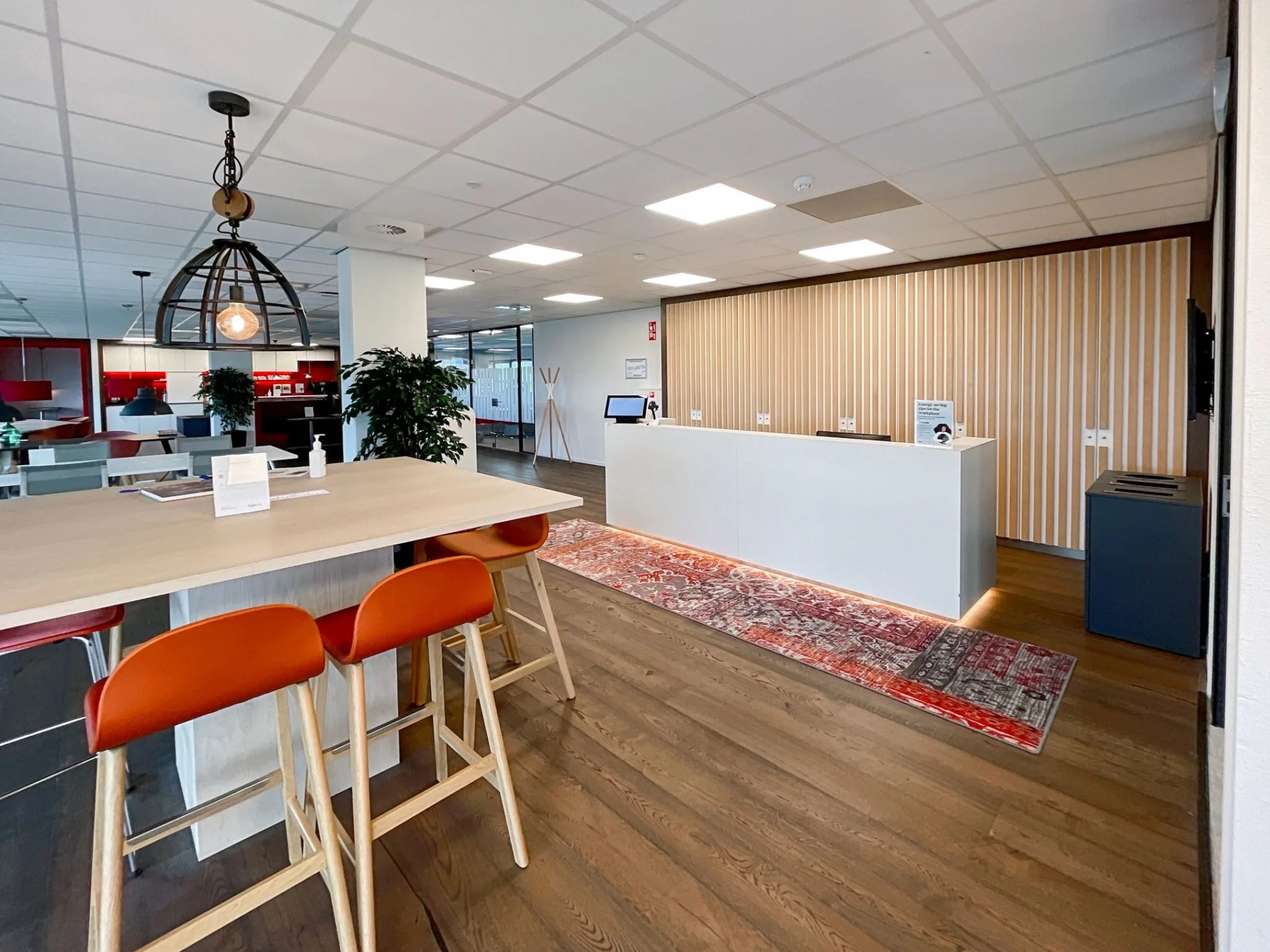 Moderne receptieruimte aan de Papendorpseweg 75 met houten vloer, witte balie en decoratieve verlichting.