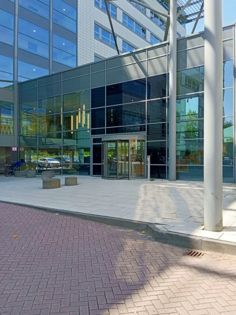 De glazen entree van het kantoorgebouw aan de Papendorpseweg 75 met een draaideur en moderne architectuur.