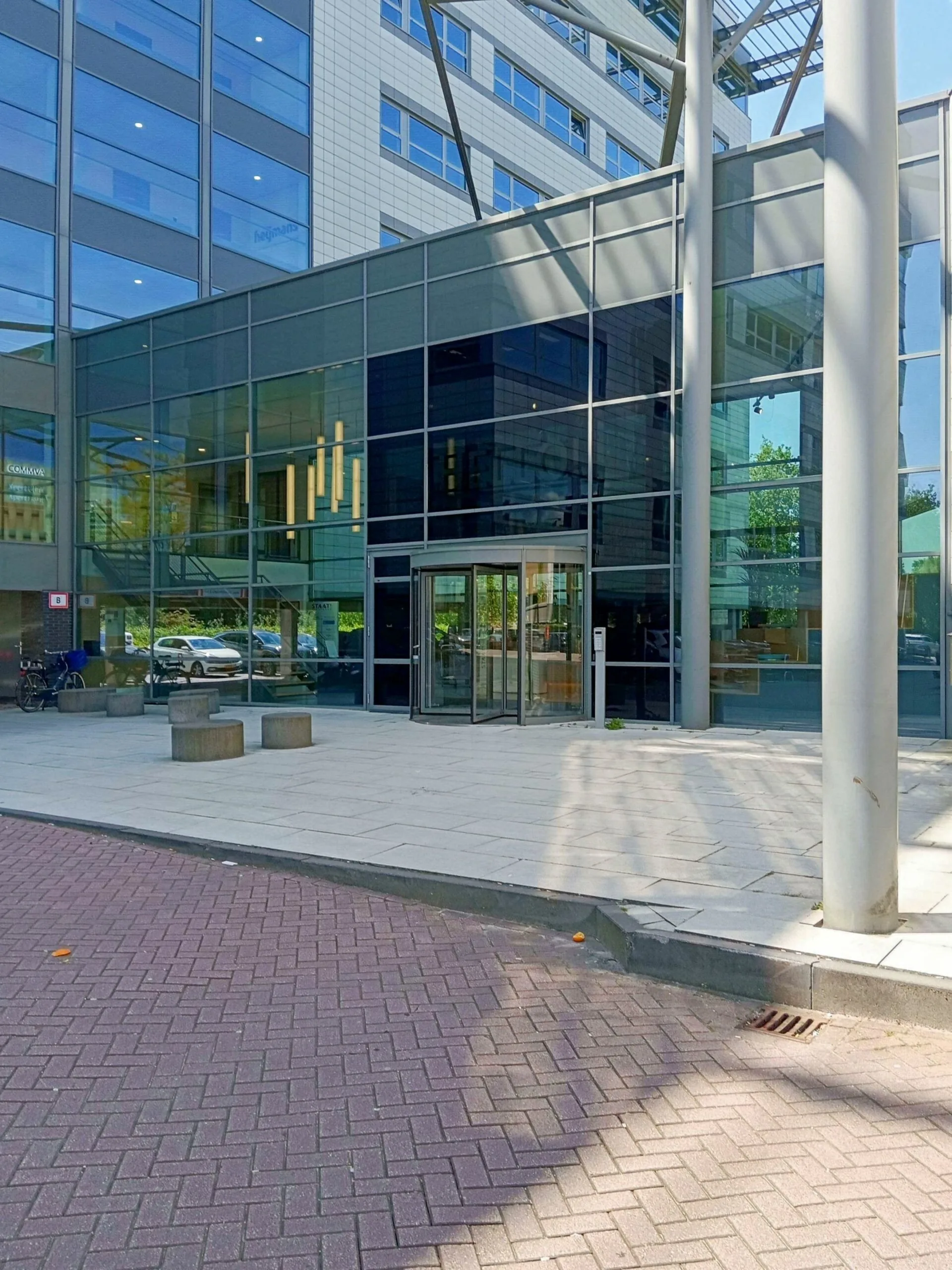 De glazen entree van het kantoorgebouw aan de Papendorpseweg 75 met een draaideur en moderne architectuur.