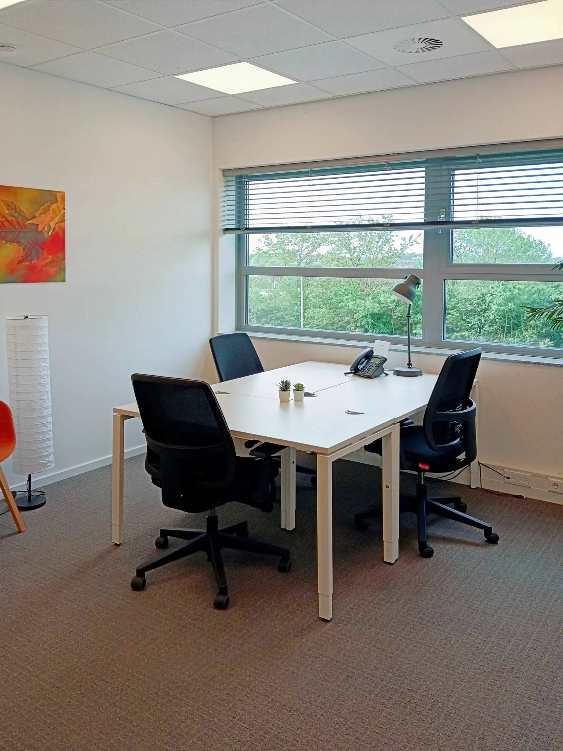 Kantoorruimte aan de Papendorpseweg 75 met vier bureaustoelen, een wit bureau, en een groot raam met uitzicht op groen.