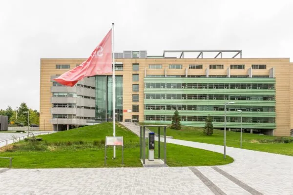 Modern kantoorgebouw aan de Papendorpseweg 95 met groene gevels, vlag en parkeersysteem op de voorgrond.