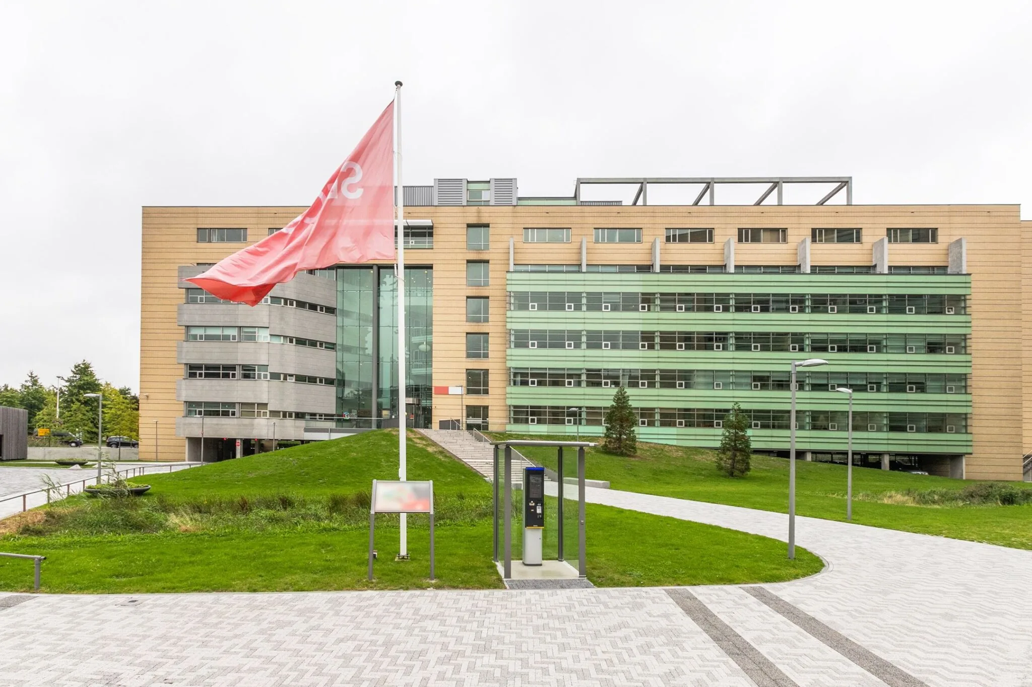 Modern kantoorgebouw aan de Papendorpseweg 95 met groene gevels, vlag en parkeersysteem op de voorgrond.