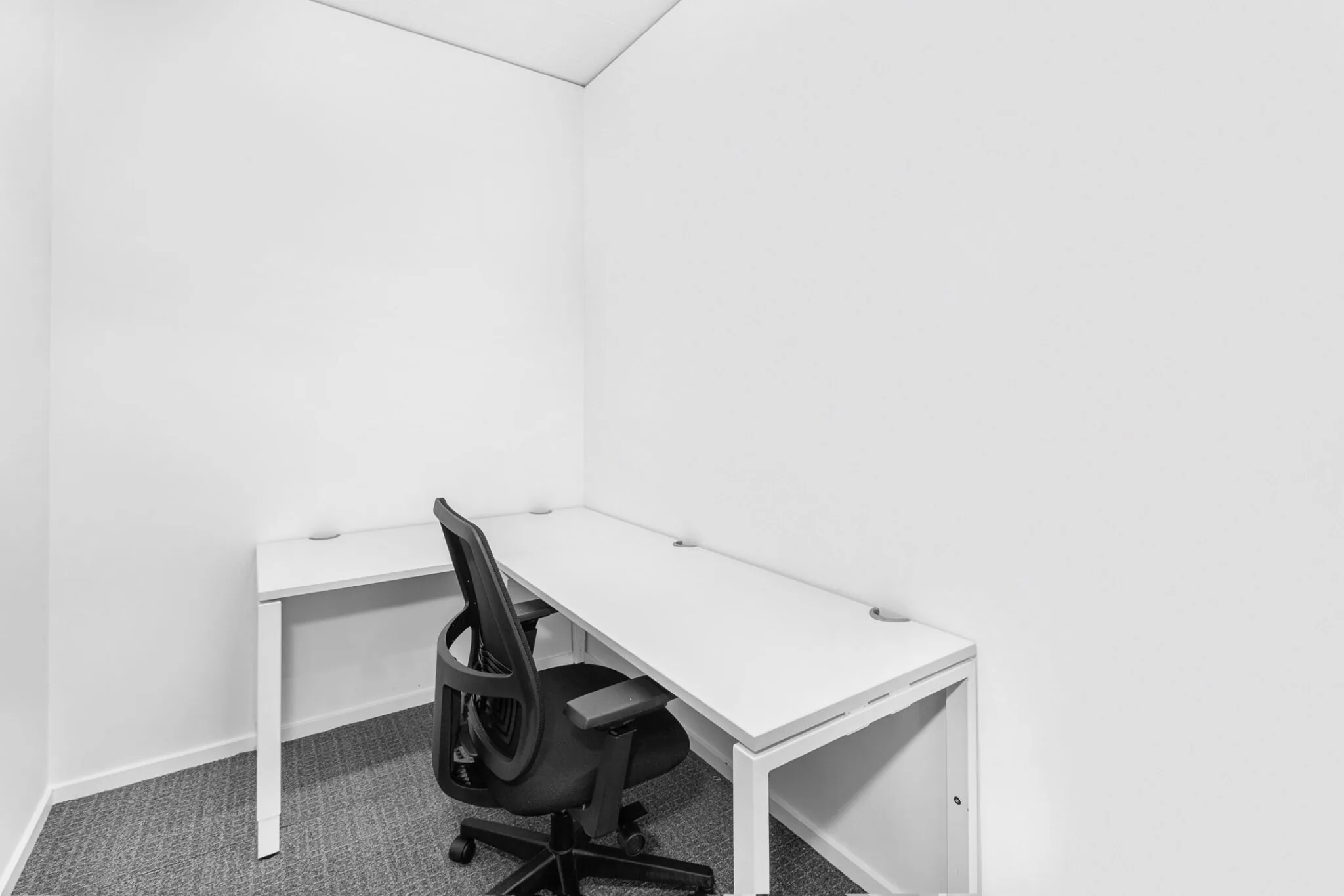 Kleine, minimalistische kantoorruimte met twee witte bureaus en een zwarte bureaustoel in de hoek van Papendorpseweg 95.