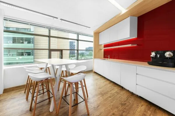 Moderne kantoorkeuken aan de Papendorpseweg 95 met witte kasten, rode achterwand, koffiemachines en hoge zitplaatsen bij een bartafel.