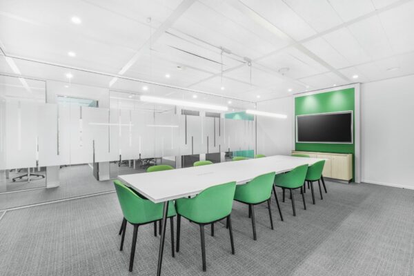 Moderne vergaderruimte aan de Papendorpseweg 95 met een lange witte tafel, groene stoelen en een groot presentatiescherm.