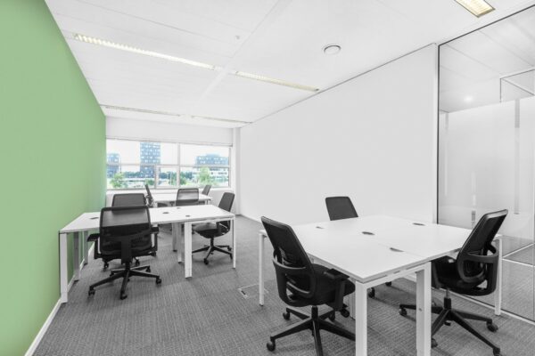 Moderne kantoorruimte aan de Papendorpseweg 95 met witte bureaus, zwarte bureaustoelen en een groene accentmuur.