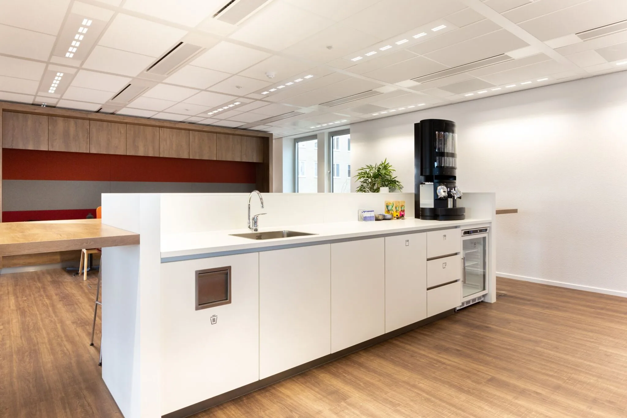 Moderne pantry in kantoor aan de Parijsboulevard 209 met koffieautomaat, gootsteen en zitgedeelte.