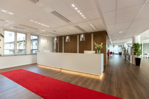 Moderne kantoorentree aan de Parijsboulevard 209 met balie, houten vloer en rode loper.