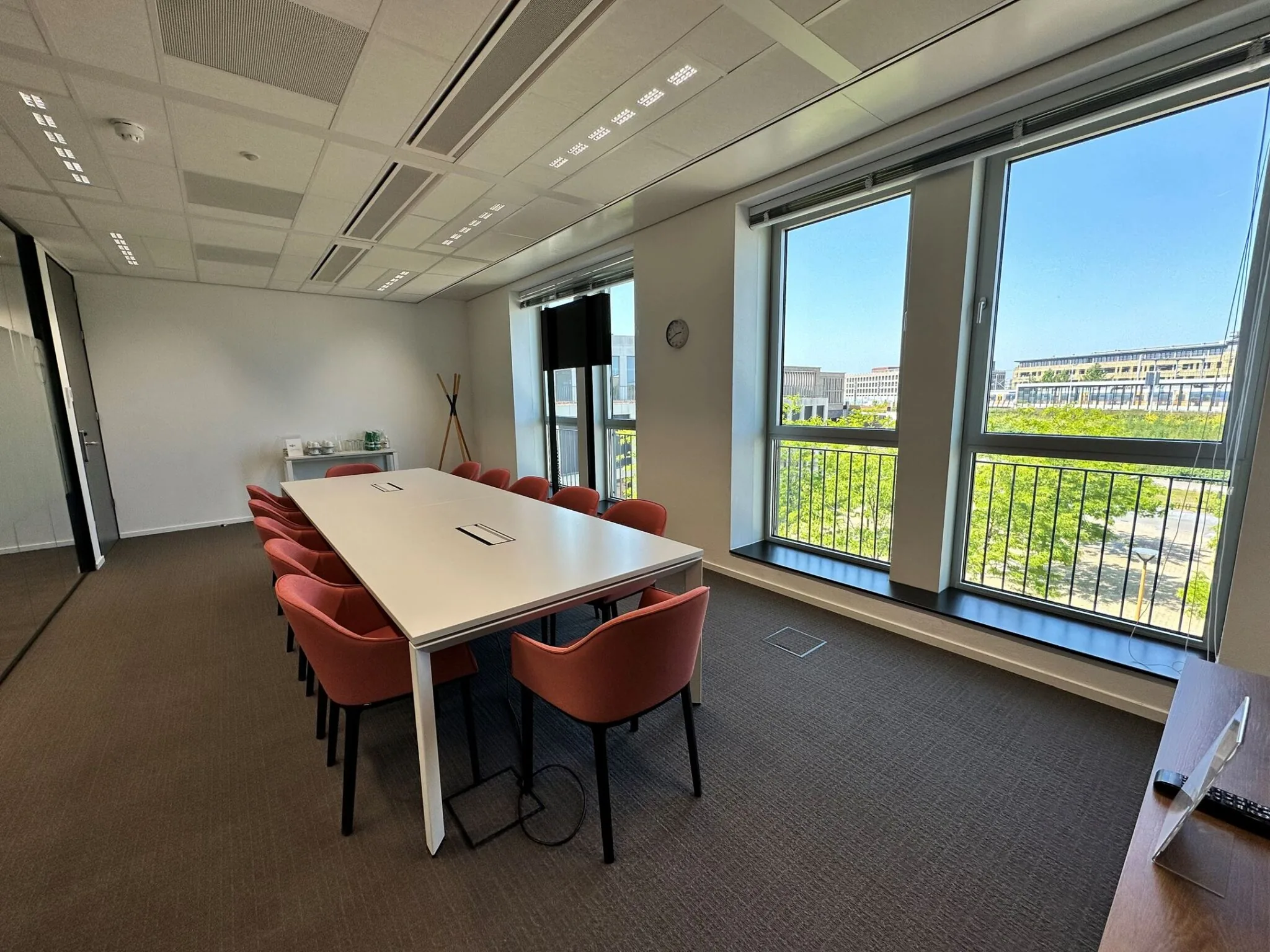 Vergaderruimte met een lange tafel, rode stoelen en grote ramen met uitzicht op de Parijsboulevard.
