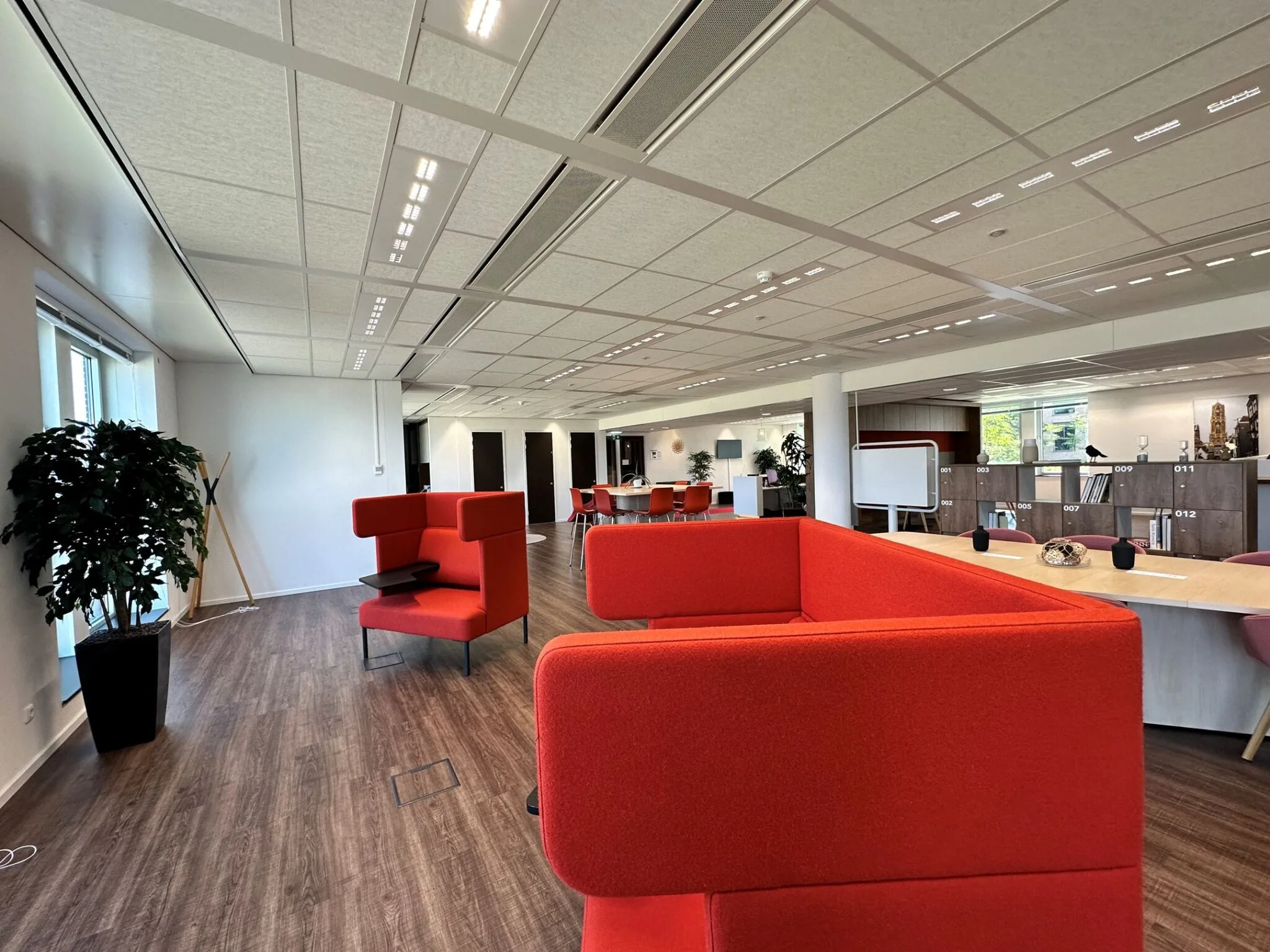 Moderne kantoorruimte aan de Parijsboulevard 209 met rode zitbanken, houten vloer en open werkplekken.