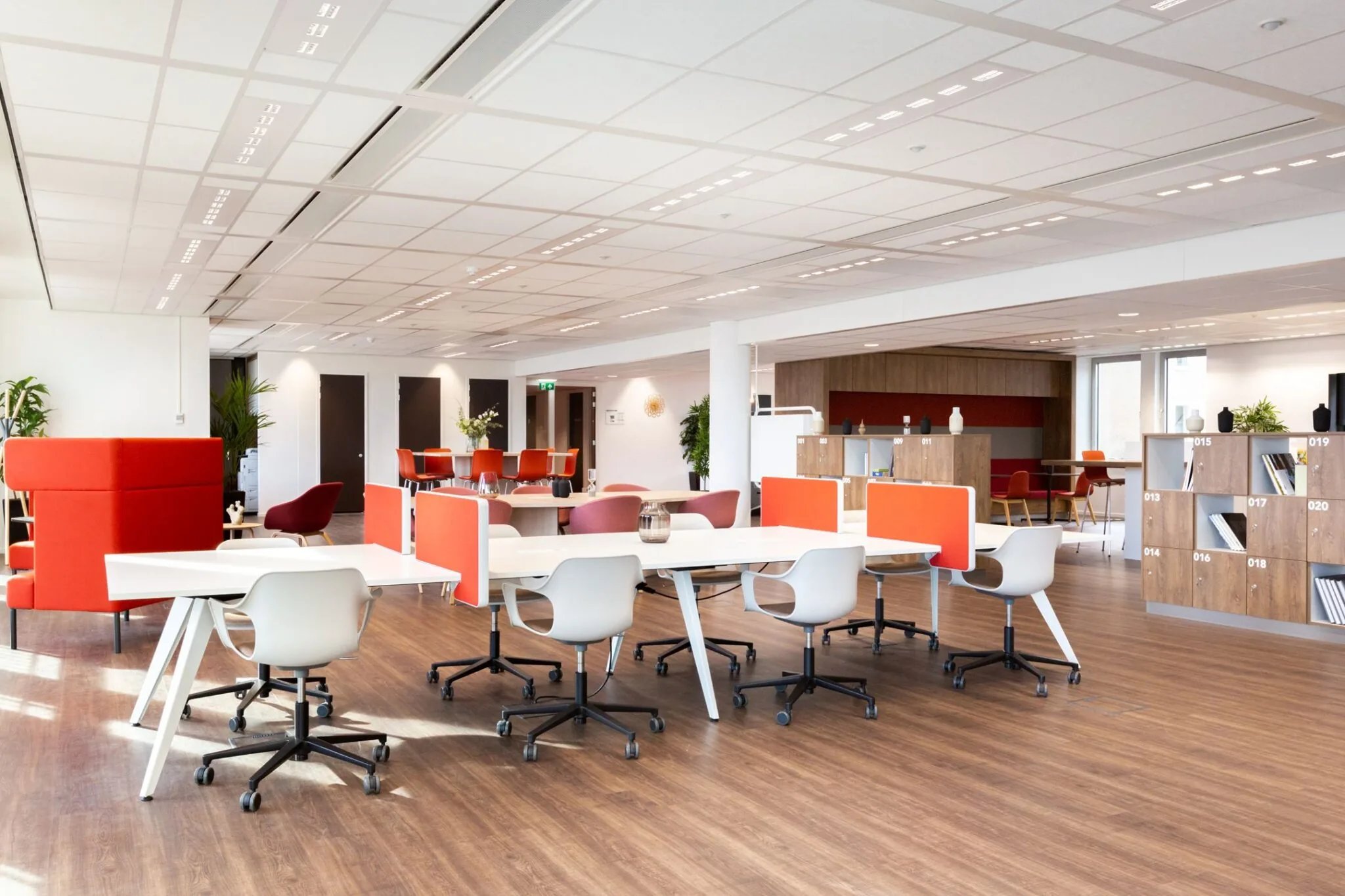 Moderne, open kantoorruimte op Parijsboulevard 209 met flexwerkplekken, oranje accenten en houten vloer.