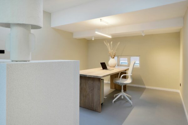 Minimalistisch ingericht thuiskantoor aan de Parkstraat 183 met houten bureau, designstoel en decoratieve vaas met droogbloemen.