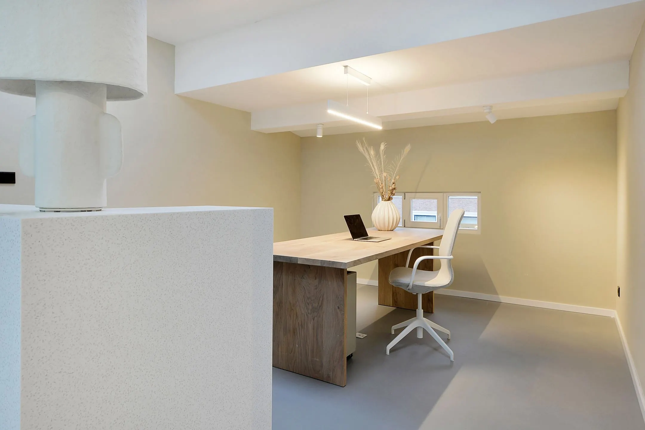 Minimalistisch ingericht thuiskantoor aan de Parkstraat 183 met houten bureau, designstoel en decoratieve vaas met droogbloemen.