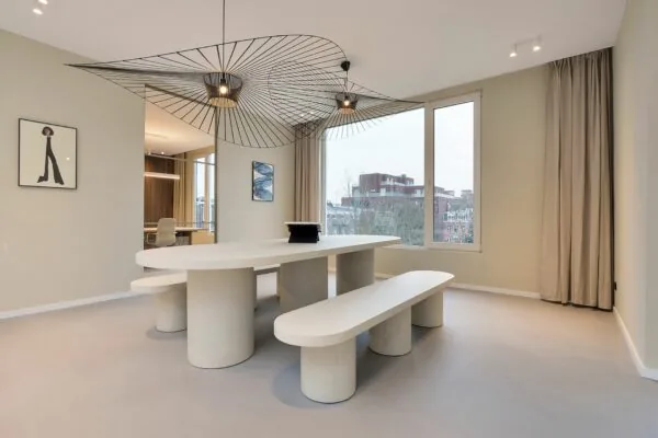 Minimalistisch ingerichte eetkamer in Parkstraat 183_5 met een ovale tafel, bijpassende banken en opvallende moderne plafondlampen.