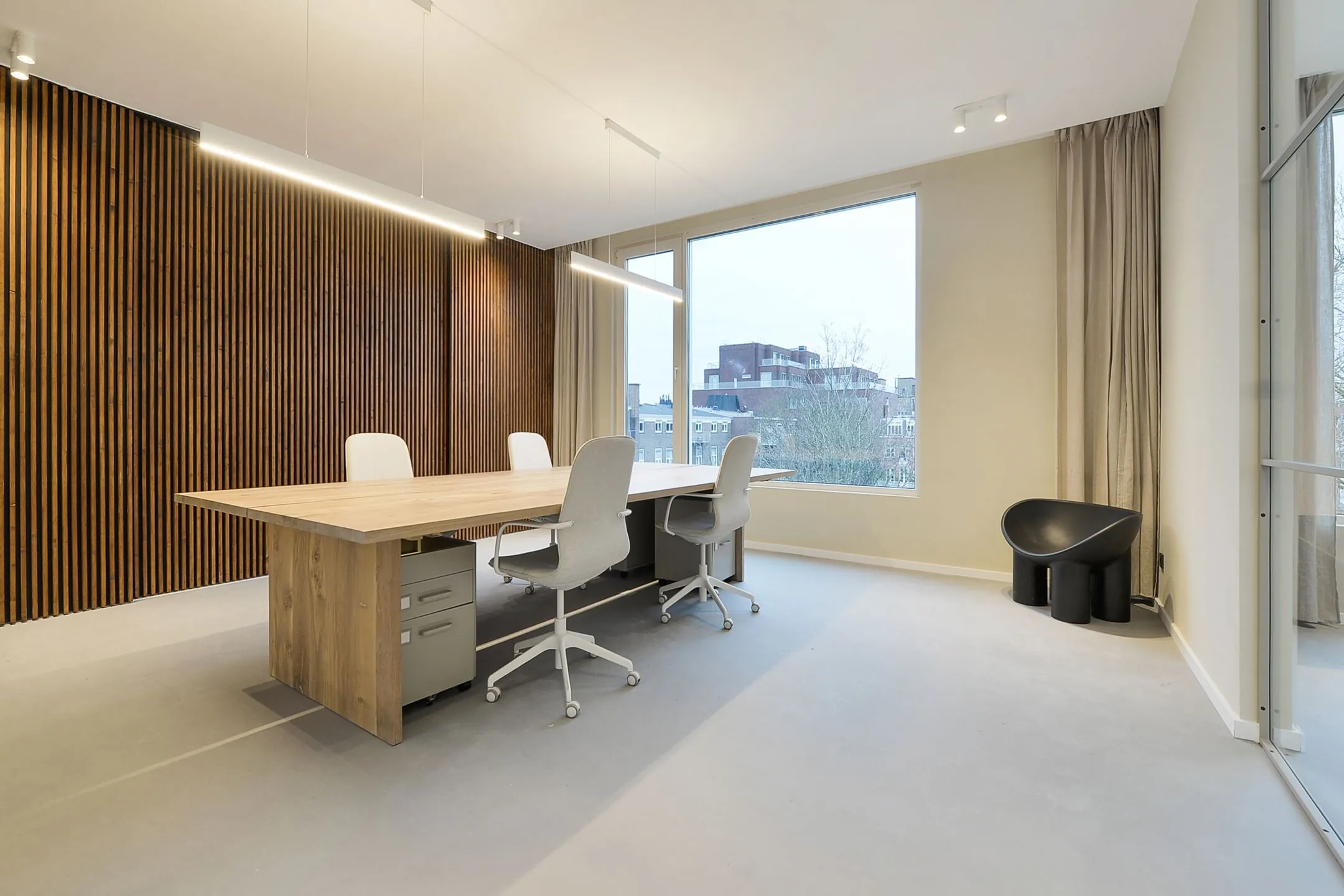 Modern ingerichte vergaderruimte in Parkstraat 183 met houten wandpanelen, grote ramen en vier bureaustoelen rond een houten tafel.