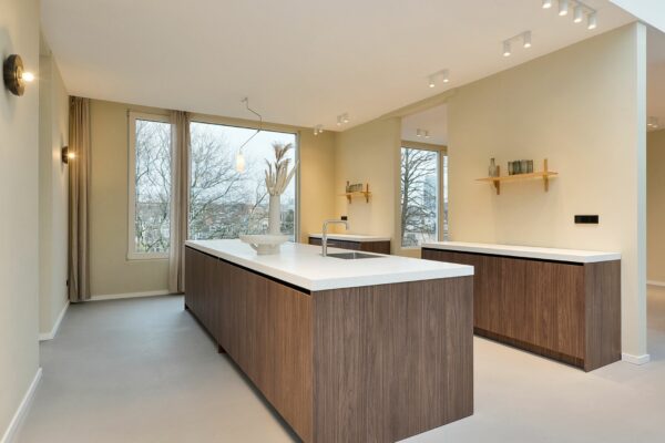 Moderne keuken in Parkstraat 183_7 met houten kasten, wit werkblad en grote ramen met uitzicht op bomen.