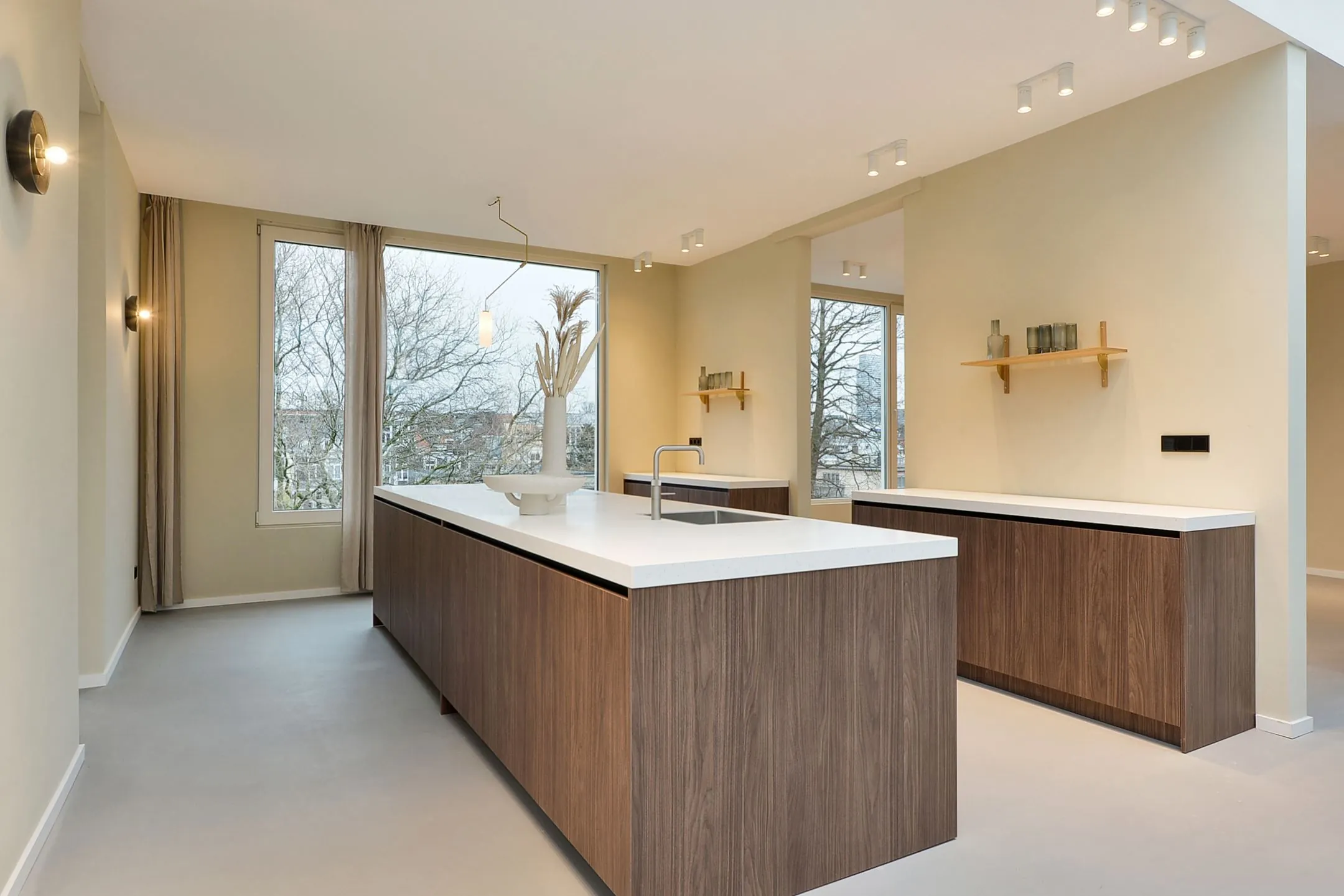 Moderne keuken in Parkstraat 183_7 met houten kasten, wit werkblad en grote ramen met uitzicht op bomen.