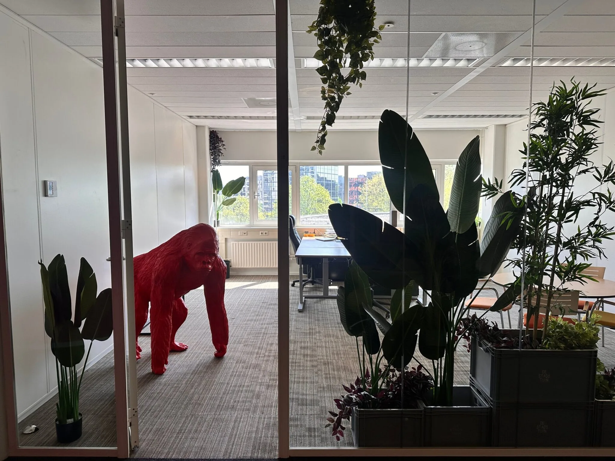 Kantoorruimte aan de Planetenweg 5 met een rode gorillabeeld en veel groenplanten.