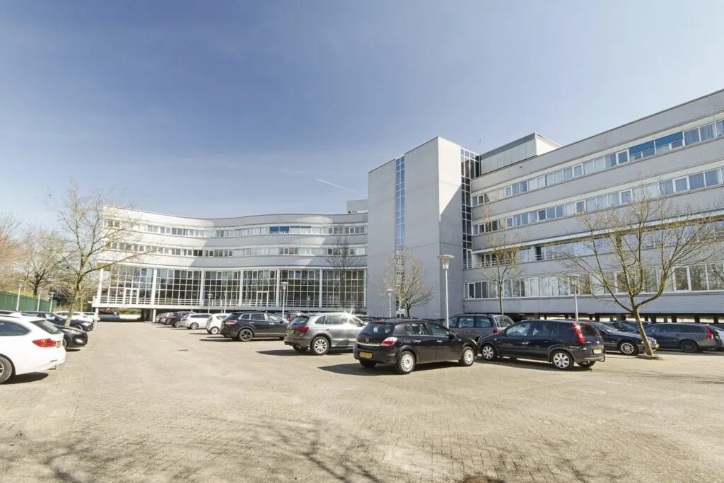 Modern kantoorgebouw aan de Planetenweg 5 met parkeergelegenheid op de voorgrond.