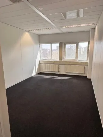 Leeg kantoorruimte met donker tapijt en grote ramen aan de Planetenweg 5.