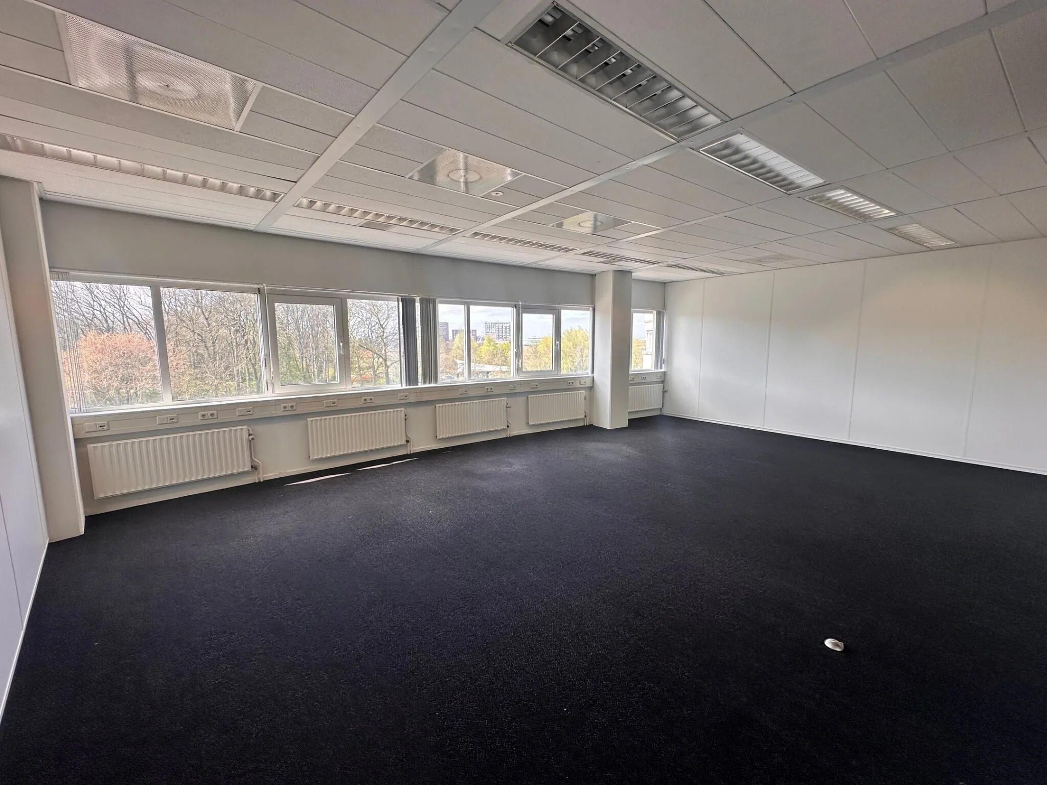 Licht en leeg kantoorruimte met grote ramen in het pand aan Planetenweg 5.