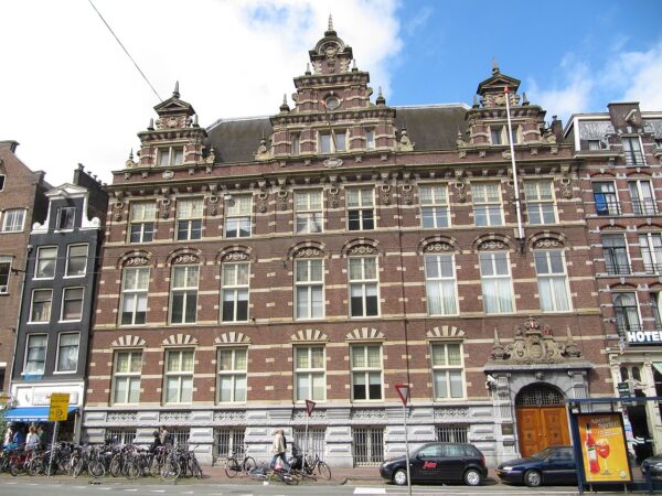Gevel van een historisch pand aan de Nieuwezijds Voorburgwal 162 in Amsterdam, met rijke architectonische details en fietsen ervoor.