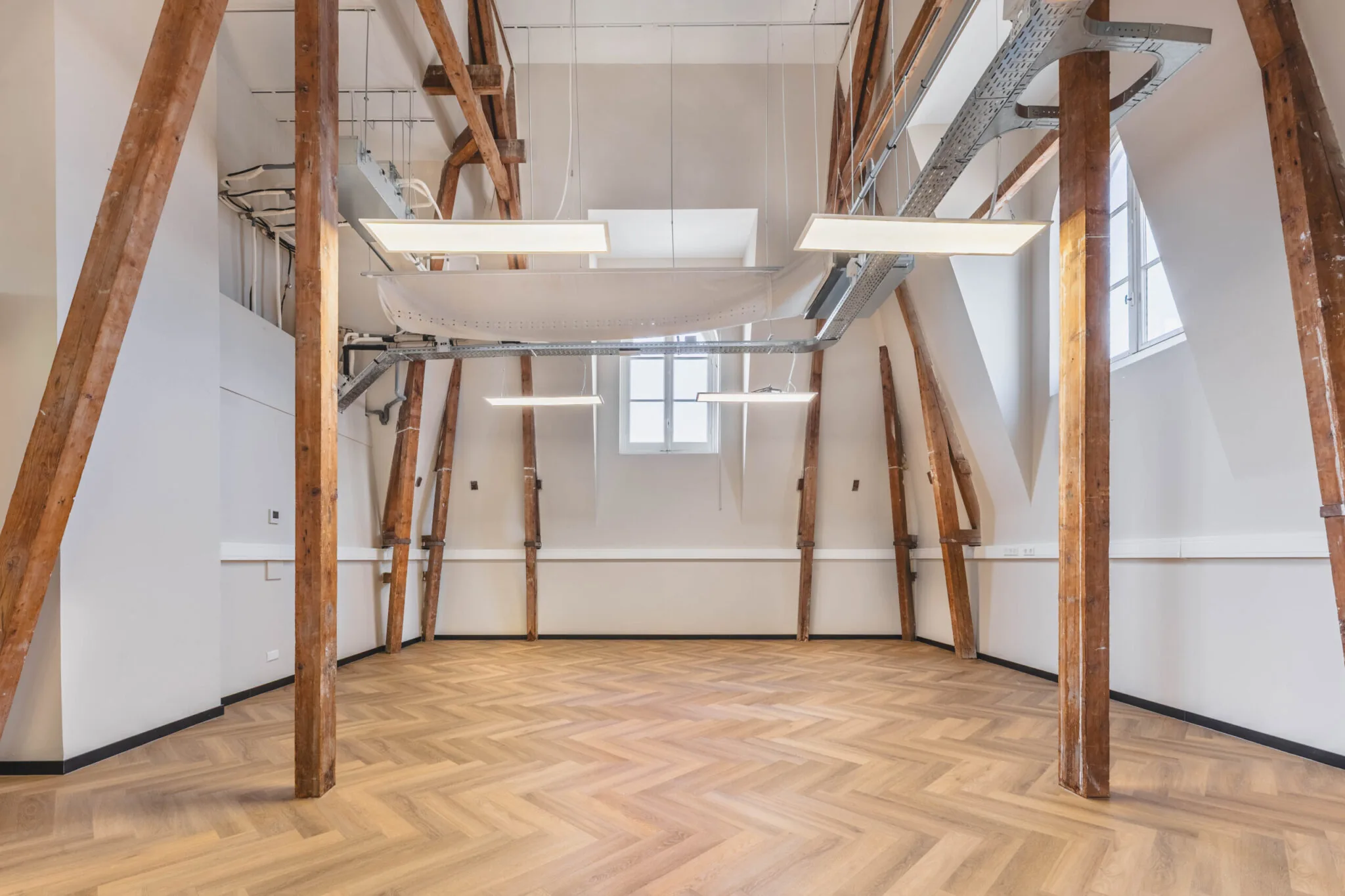 Licht en modern afgewerkte ruimte in Raamplein 1-27 met houten balkenconstructie, visgraatvloer en hoge plafonds.