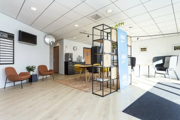 Moderne wachtruimte in kantoorpand Ravelijn1 met zitplaatsen, vergadertafel en FNV-banner.