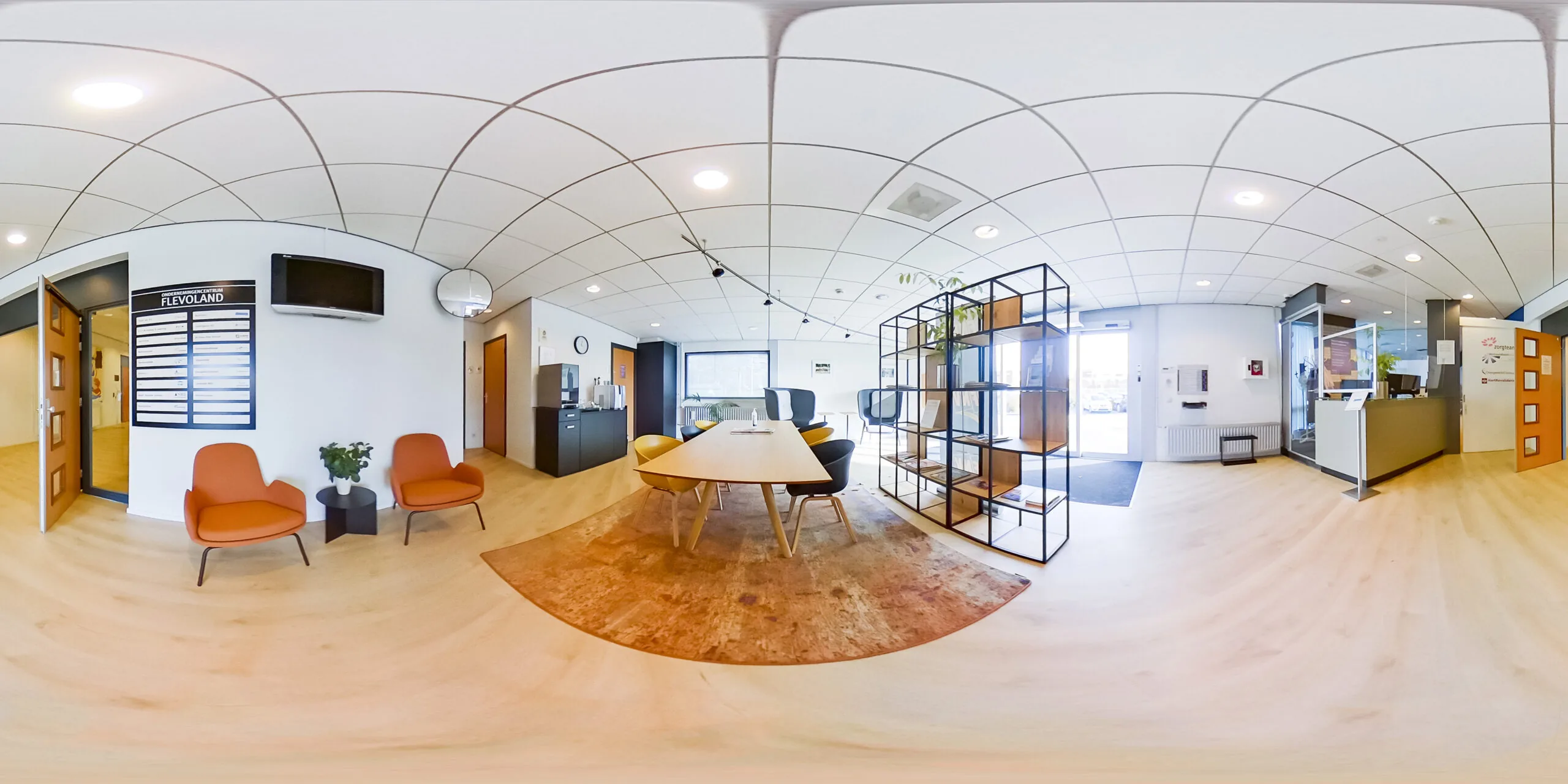 Moderne wachtruimte en receptie van Gezondheidscentrum Ravelijn 1 in Flevoland, met zitplekken, een balie en informatierek.