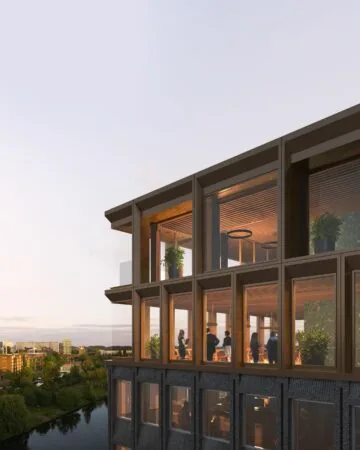 Moderne gevel van het gebouw aan de Rijnsburgstraat 9 met grote ramen en mensen in een sfeervol verlichte ruimte met uitzicht op het water.