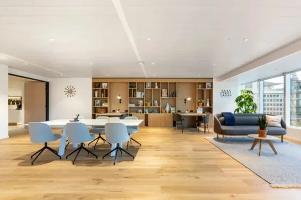 Moderne en licht ingerichte kantoorruimte in Rotterdam Airportplein 22 met houten vloer, vergadertafels, boekenkasten en zithoek bij het raam.