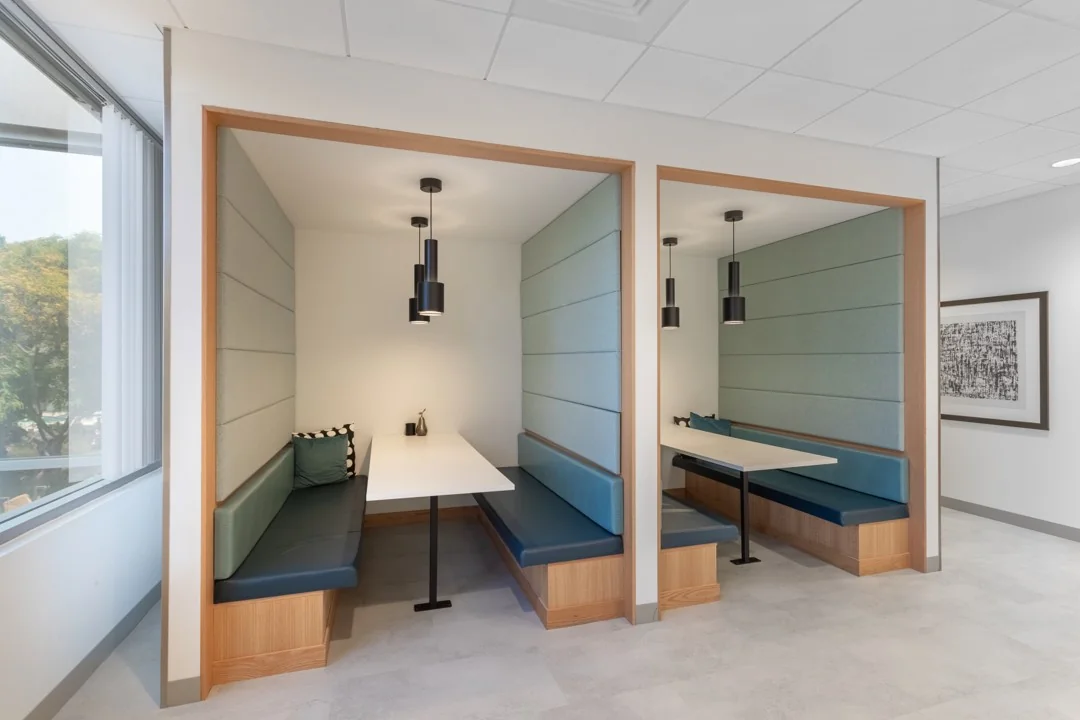 Twee moderne zitnissen met blauwe banken en hanglampen in een kantoorruimte in Rotterdam Airportplein 22.