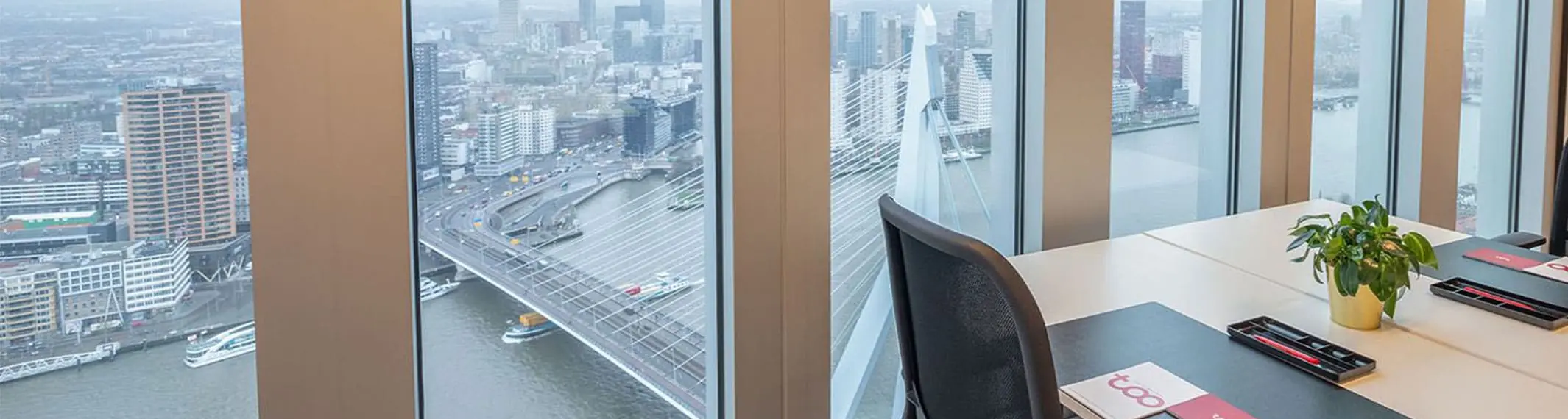 Moderne werkplekken met een panoramisch uitzicht op de Erasmusbrug en de skyline van Rotterdam.