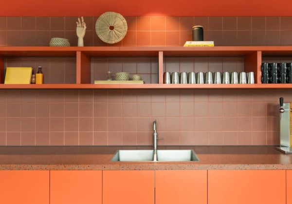 Moderne oranje keuken met een dubbele gootsteen en open planken vol decoratieve objecten en metalen bekers.
