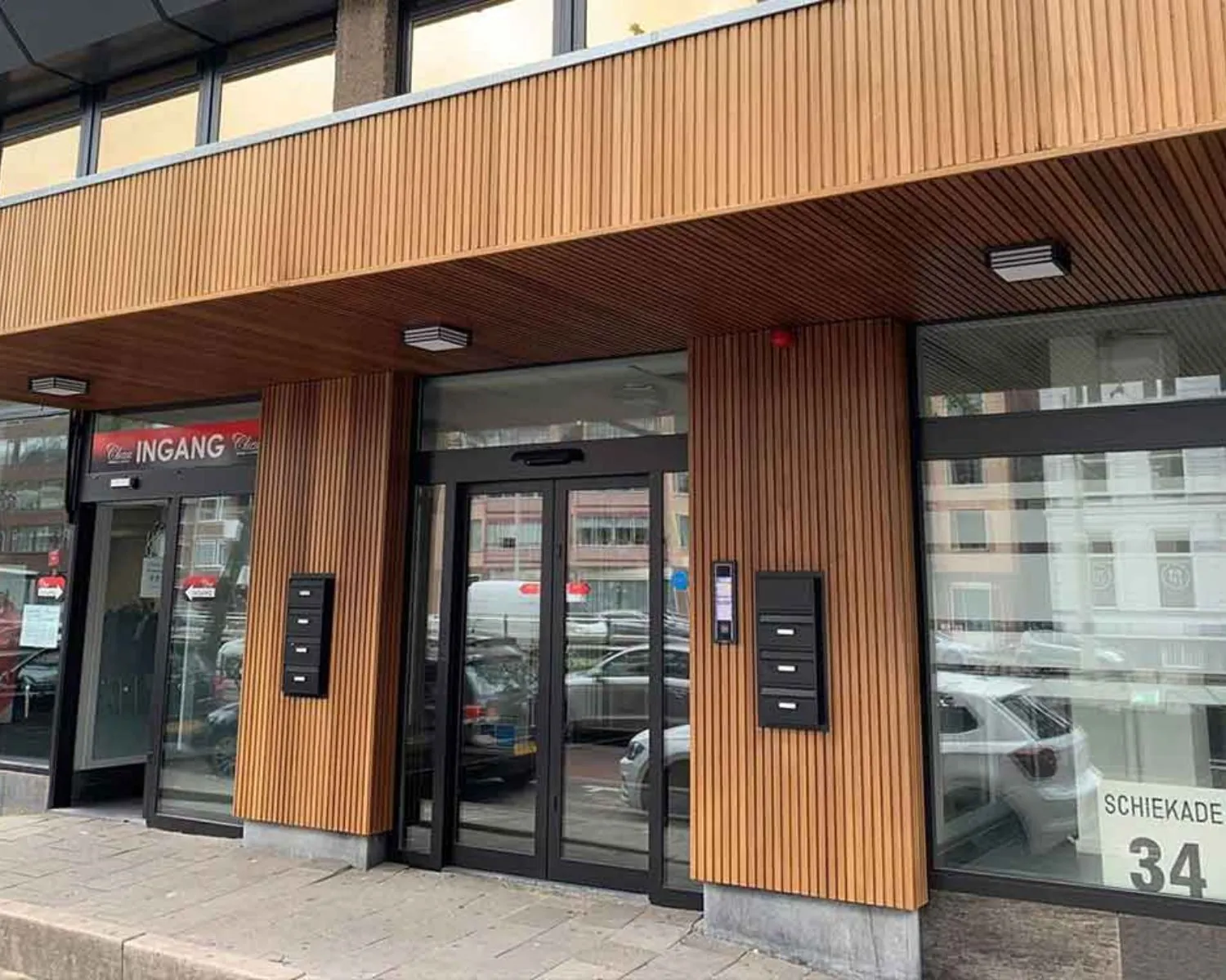 Voorgevel van het kantoorpand aan Schiekade 34 in Rotterdam met houten bekleding en glazen entreedeuren.