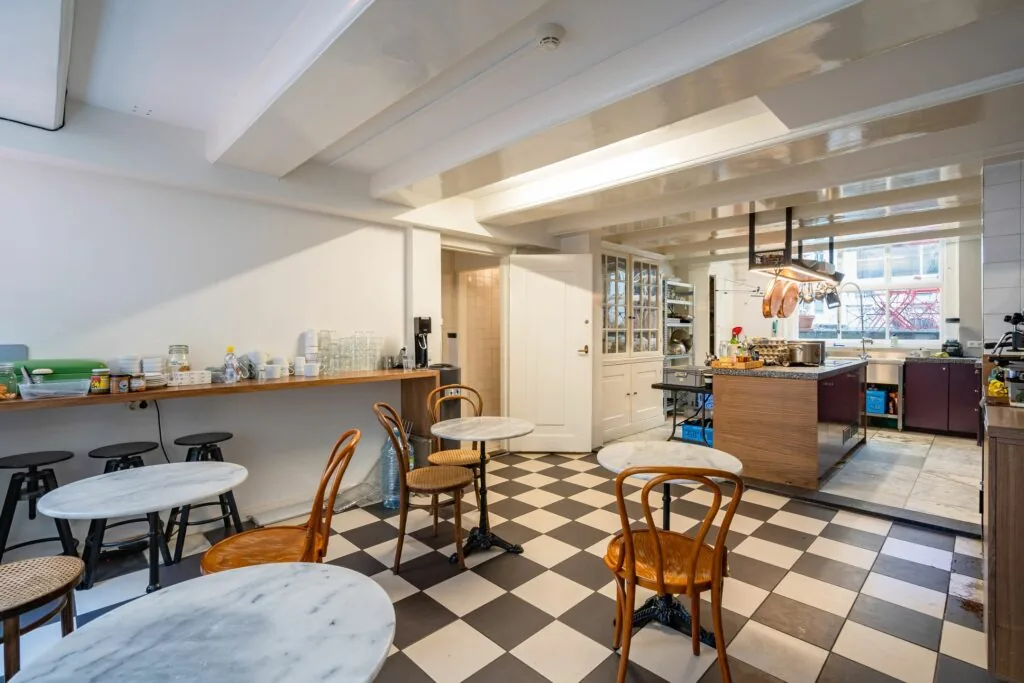 Gerenoveerde keuken en eetruimte met zwart-wit dambordvloer in Singel 258_3, ingericht met marmeren tafels en houten stoelen.