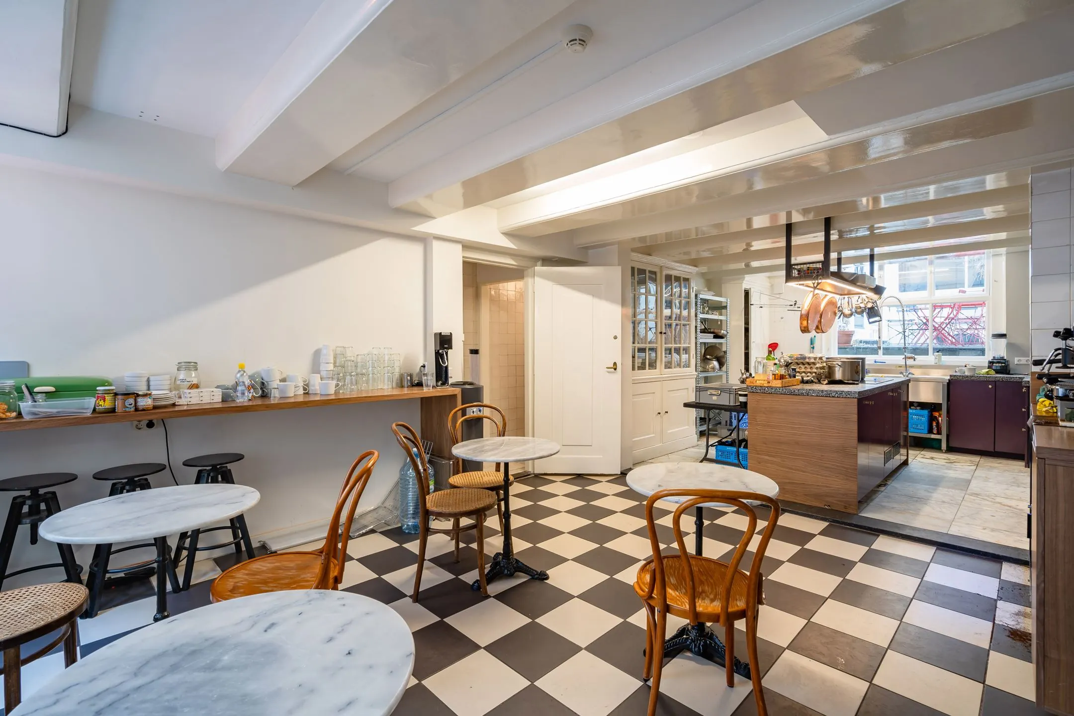 Gerenoveerde keuken en eetruimte met zwart-wit dambordvloer in Singel 258_3, ingericht met marmeren tafels en houten stoelen.
