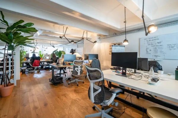 Modern kantoorinterieur op Singel 258 met houten vloer, witte bureaus, ergonomische stoelen en groene planten.