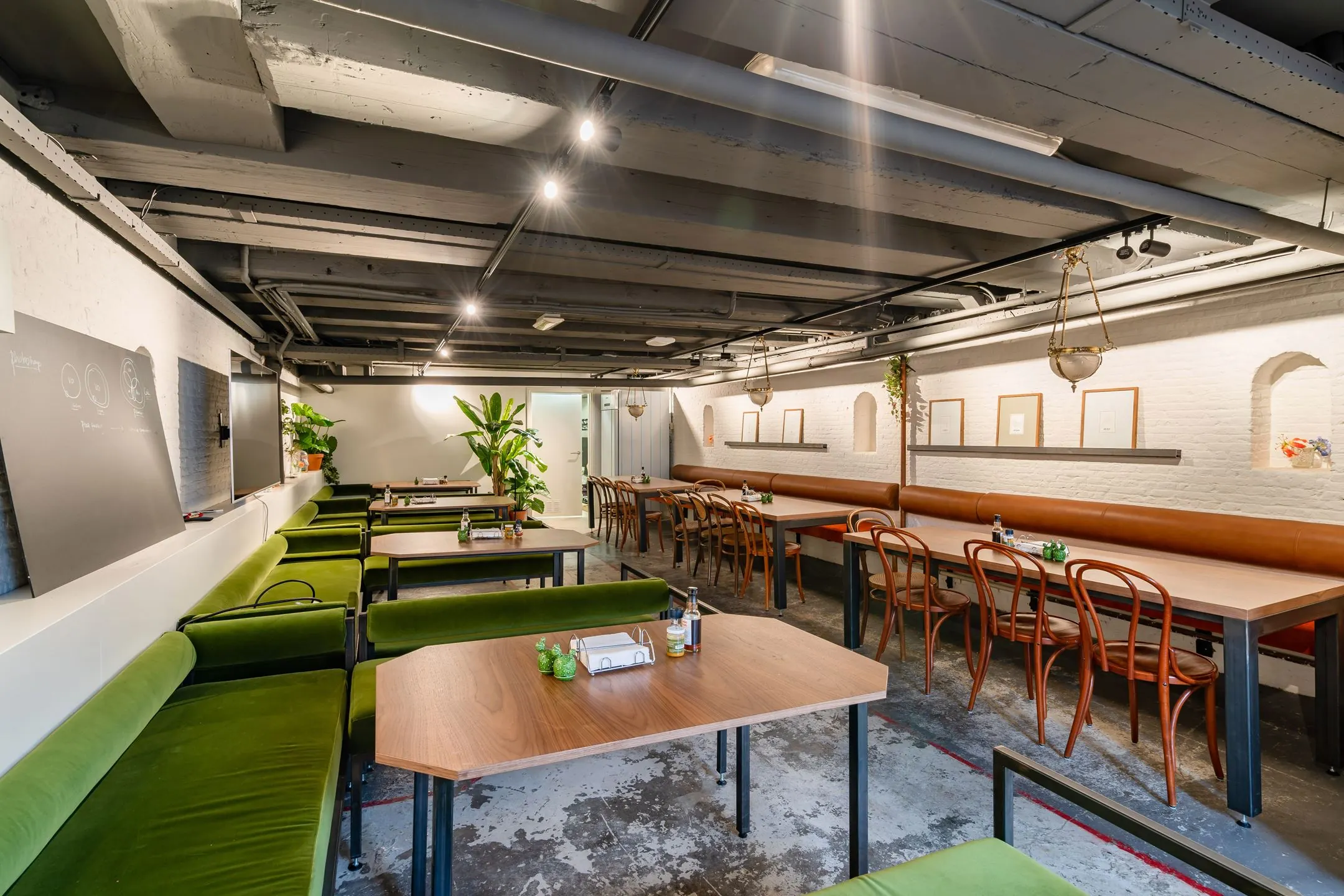 Moderne vergaderruimte Singel 258 met houten tafels, groene en bruine zitplaatsen en industriële details.