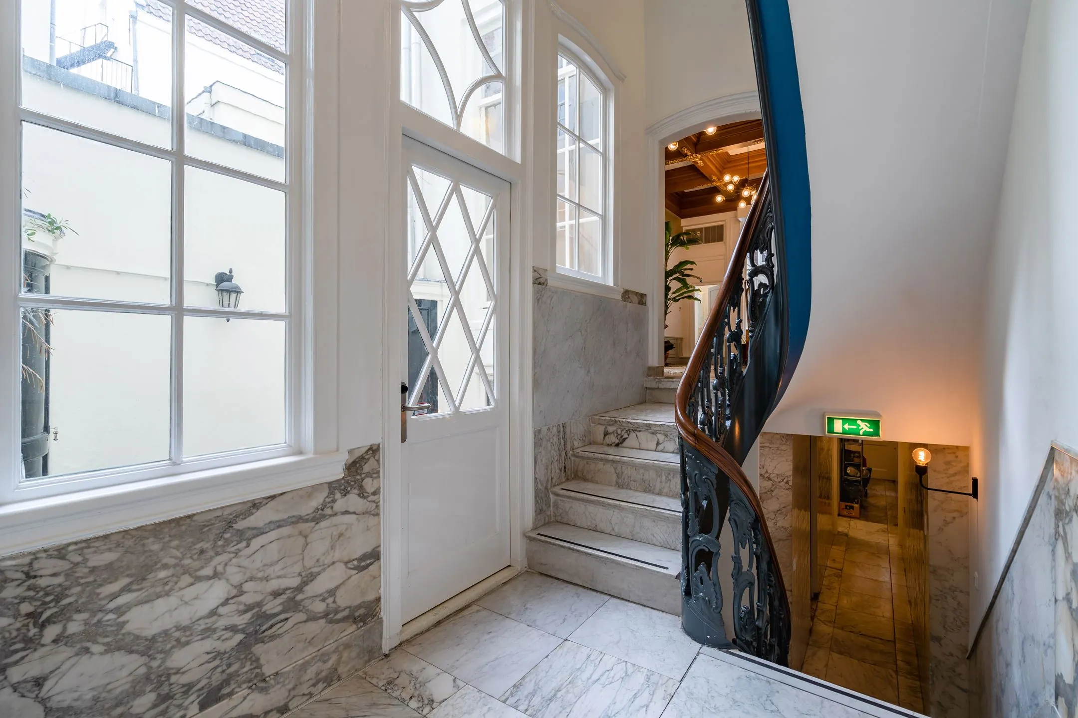 Marmeren trappenhuis met sierlijke leuning en houten accenten in Singel 258_8, met uitzicht op een lichte binnenplaats.