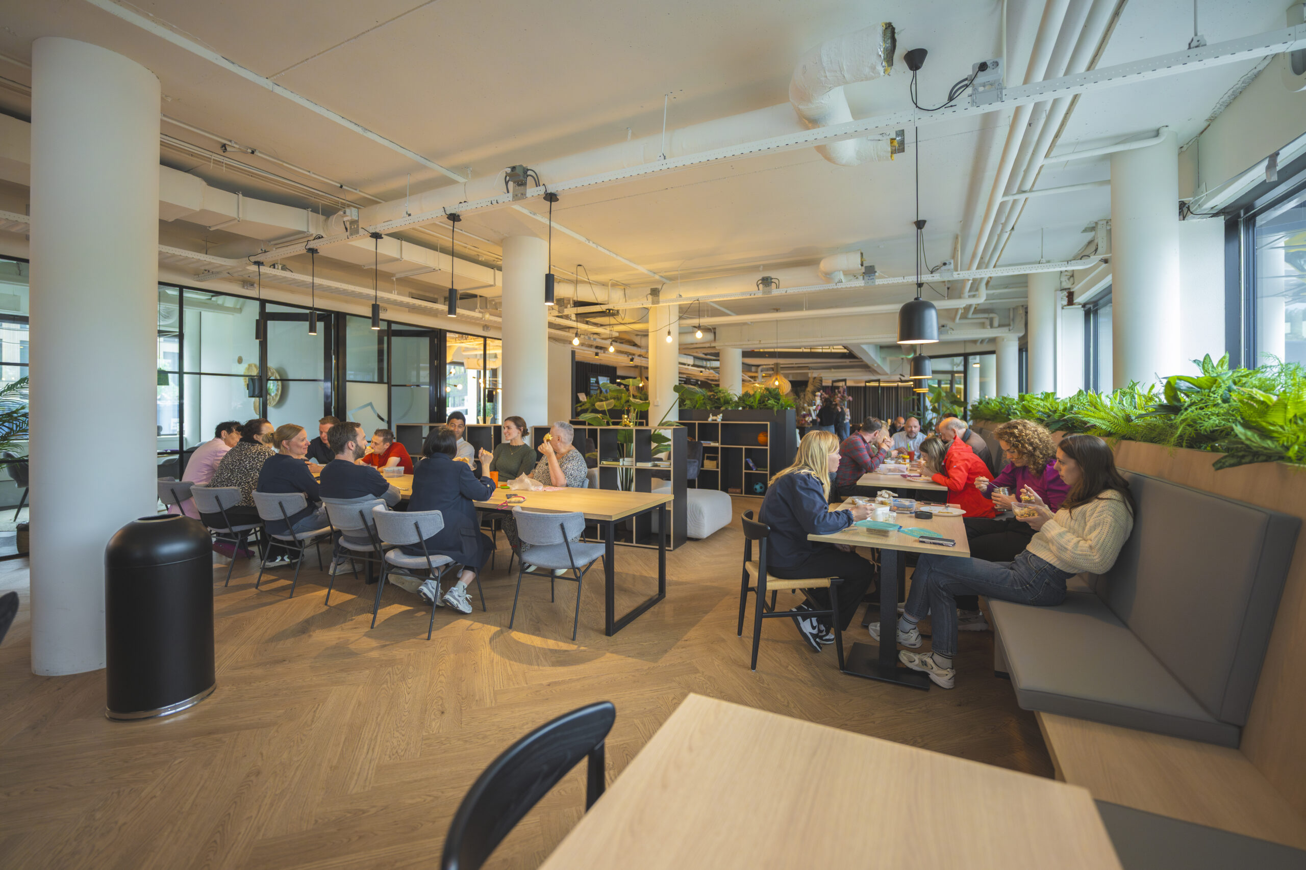 Mensen zitten samen aan tafels in een warme, open ruimte die dienstdoet als sociaal hart.