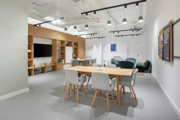 Moderne gemeenschappelijke werkruimte in Spaces Expo in Boekarest met houten tafels, grijze stoelen, open wandkasten en loungegedeelte.
