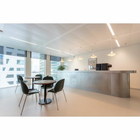 Moderne bedrijfsruimte met een strakke receptiebalie, zitgedeelte en grote ramen met uitzicht op kantoorgebouwen.