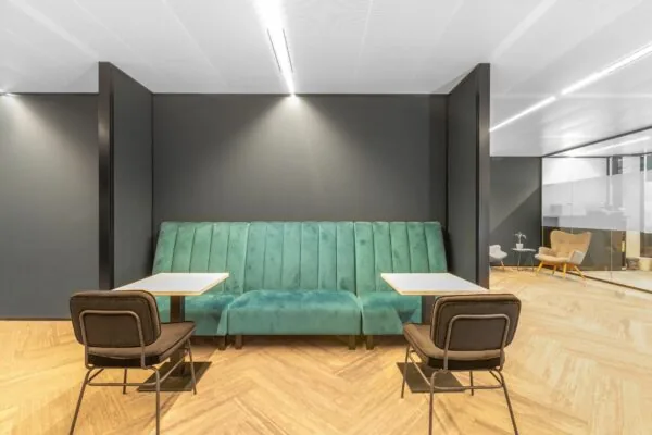 Moderne zithoek in kantoorruimte Stadsplateau 7 met groene bank, twee tafels en bruine stoelen.