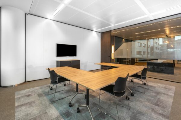 Vergaderruimte met U-vormige houten tafel, zwarte stoelen, een flatscreen en glazen wand aan het Stadsplateau 7.